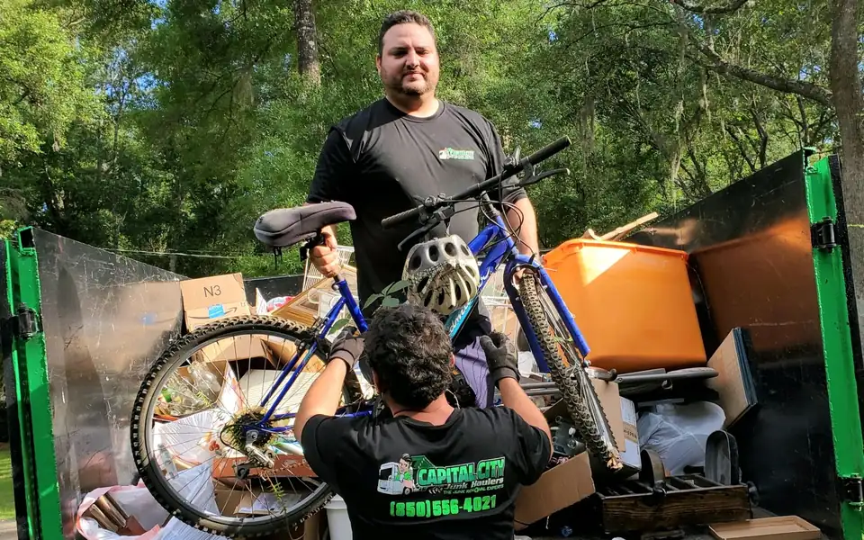 Two crew members loading a bicycle into a truck full of items from a cleanout