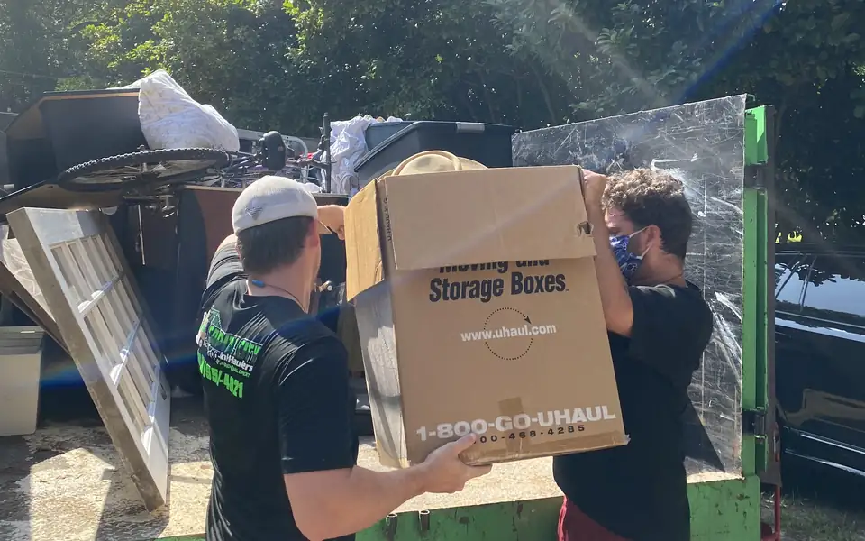 Capital City Junk Haulers crew loading boxes and household items into a junk removal truck