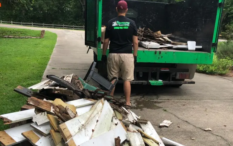 Capital City Junk Haulers crew member hauling away a pile of old lumber and debris